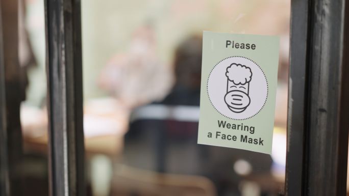 大流行期间办公室玻璃墙上的标志，必须始终佩戴防护口罩