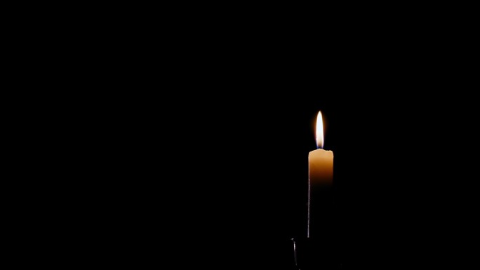 一个点燃的蜡烛火焰在黑色背景上一路燃烧的时间流逝