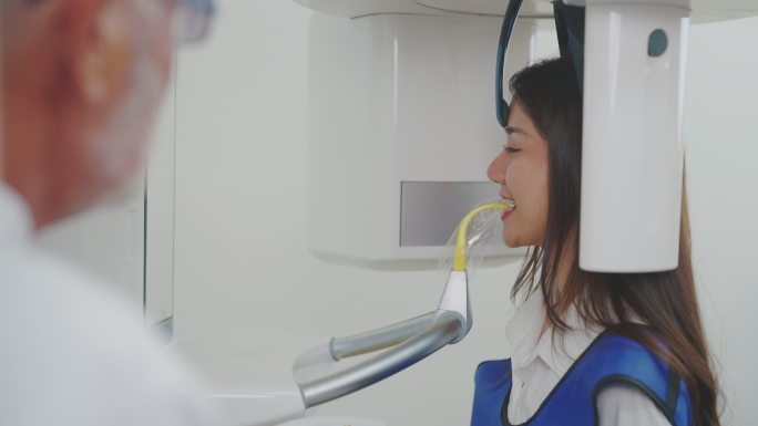 牙科诊所牙医培训室的高级牙医和女患者使用扫描仪扫描牙齿。