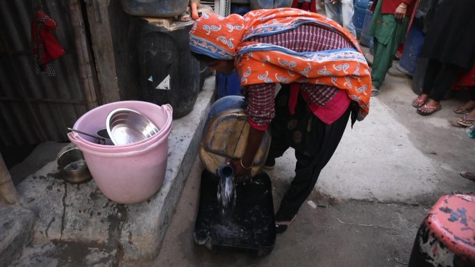 印度德里南部居民拎塑料桶去接水