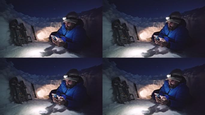 成熟的游客晚上在雪地里使用手机。在大自然中独自在冬山露营。