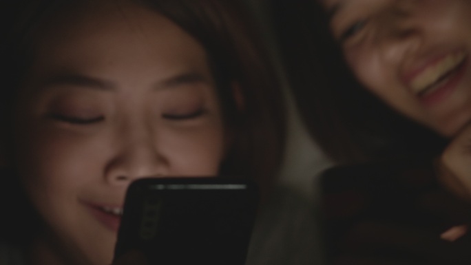美丽的亚洲女人在床上使用手机