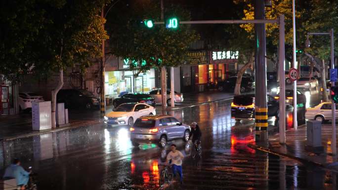 4K下雨的夜晚城市街道路口路灯车流对比