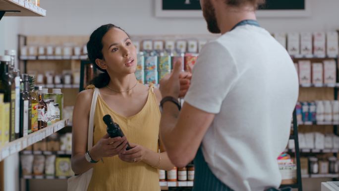 一位女性在她正在购物的商店接受良好的客户服务。一位年轻女子与店员谈论货架上的一种新产品。超市老板或售