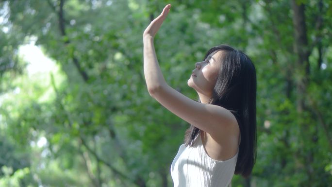 女孩抬头仰望阳光伸手遮挡阳光