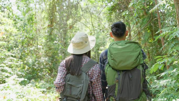 亚洲男女背包客朋友一起在森林野外旅行。迷人的年轻夫妇在夏天的假期旅行中，带着快乐和乐趣漫步和探索自然