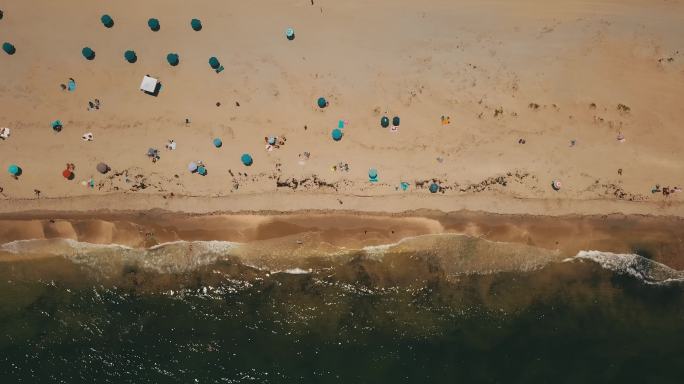 2022年一个炎热的周末夏日，佛罗里达州博因顿海滩，彩色海滩雨伞旁边的水波流向海岸线
