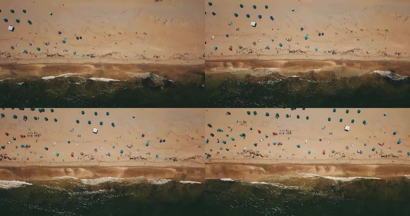 2022年一个炎热的周末夏日，佛罗里达州博因顿海滩，彩色海滩雨伞旁边的水波流向海岸线