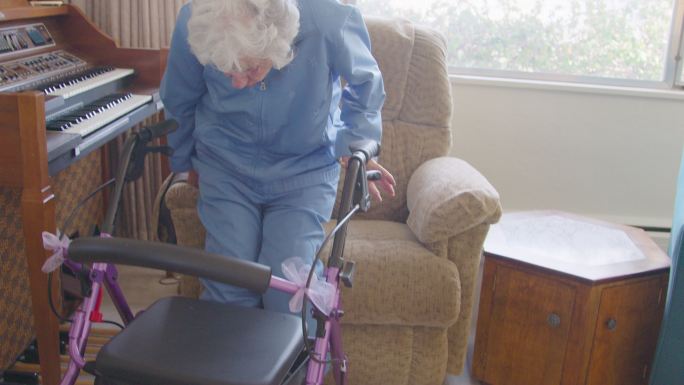 100岁的老年妇女从躺椅上用移动步行器慢慢站起来