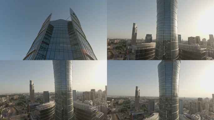 反射蓝天的玻璃摩天大楼。FPV无人机向下移动并远离建筑物