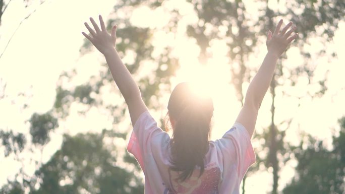 夕阳下女孩张开双臂朝着太阳挥手