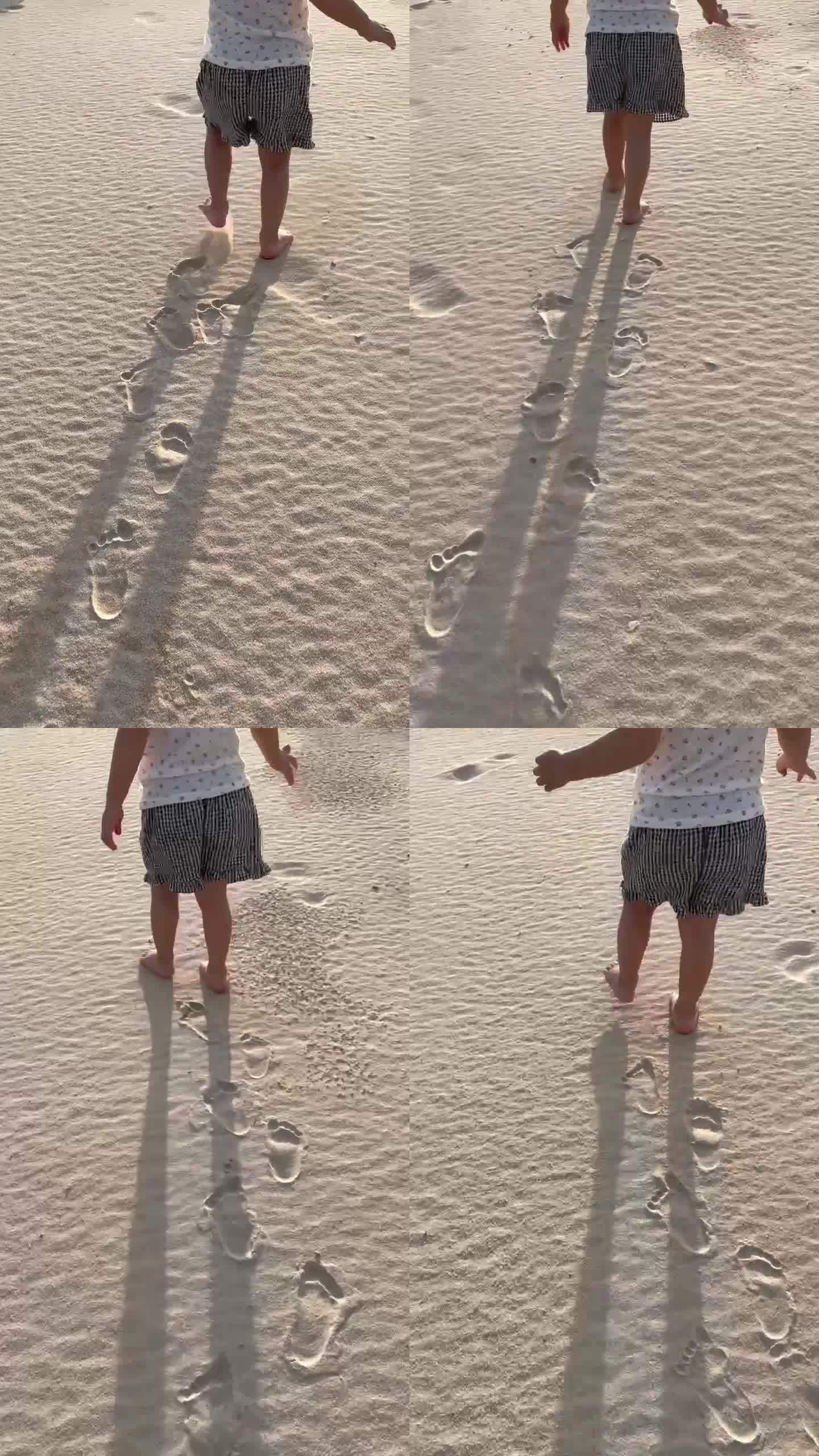 沙滩上一个赤脚的可爱小孩一步一个脚印走着