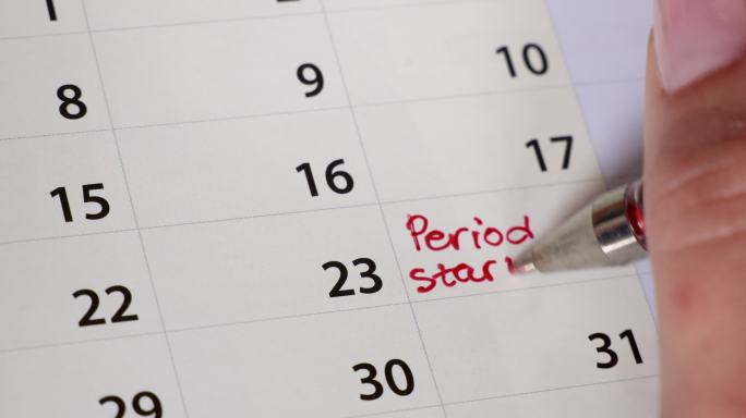 女性用红笔在日历上书写月经提醒