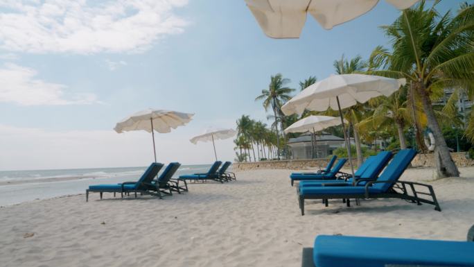泰国华欣白色沙滩上的沙滩椅，带着阳伞。