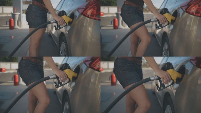 美女在加油站加油补油在车旁