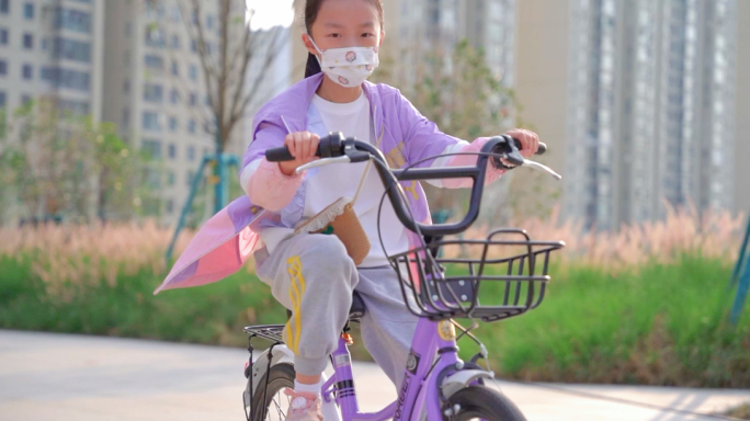戴着口罩骑自行车的小女孩
