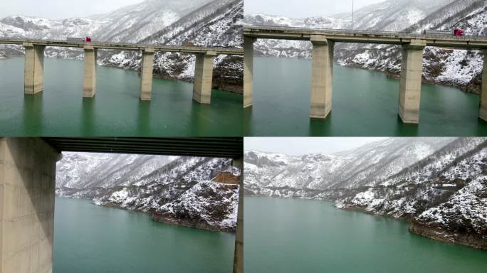 冬季飞车在冰河上过桥，桥梁和雪山的空中拍摄，两座雪山之间的桥梁连接，空中雪景，桥上的红色卡车，下雪天