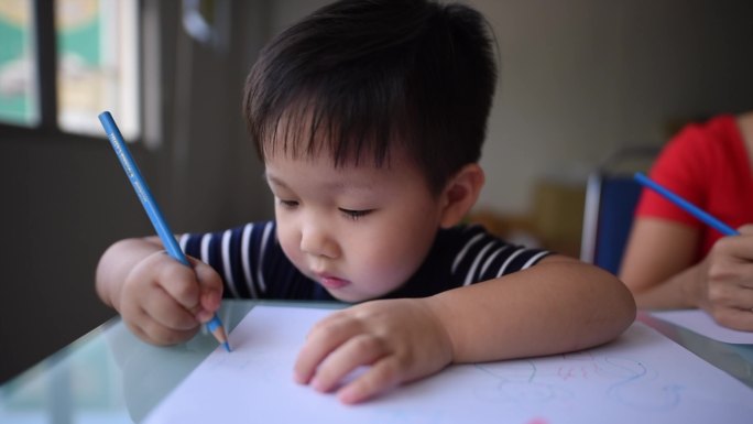 亚裔中国微笑可爱的小男孩在美术课上用彩色铅笔画画