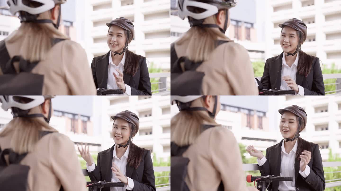 从肩上看，这位年轻的亚洲女商人戴着头盔，背着商务背包，与骑着电动踏板车上班的漂亮年轻同事会面。他们在
