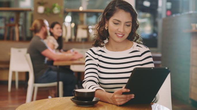 一名年轻女子在咖啡馆喝咖啡并使用数字平板电脑的4k视频片段