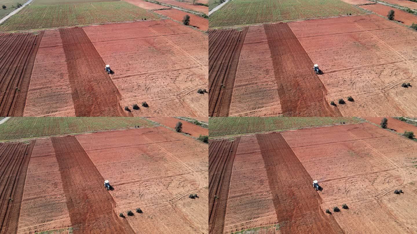 无人机视图，鸟瞰拖拉机在农田中开沟播种农用拖拉机。