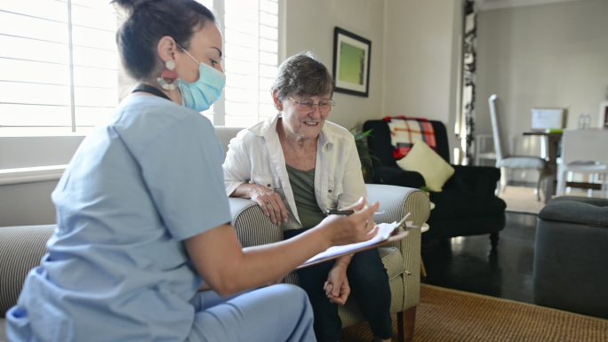 老年妇女在家访期间与医护人员交谈