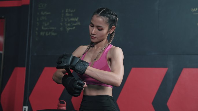 亚洲年轻女子在日常训练前戴上拳击手套。