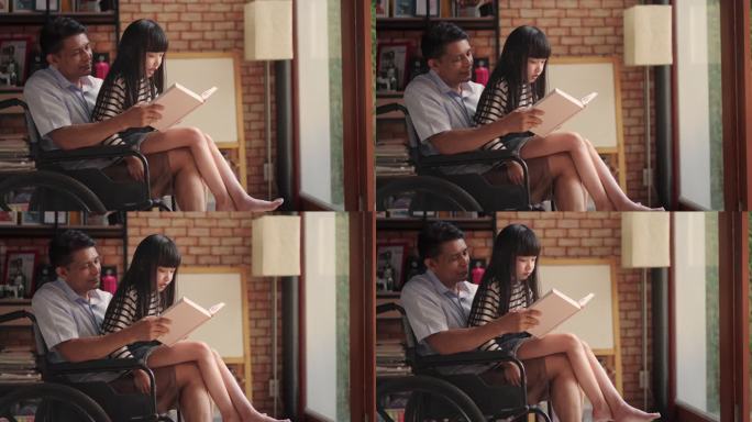侧视坐在轮椅上的亚洲高龄男子教十几岁的女孩在一个膝盖上读一本大书，一起在家背诵。多代家庭周末活动