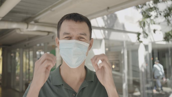 快乐的混合亚洲中年男子摘下医用面罩的肖像，新的正常健康生活方式