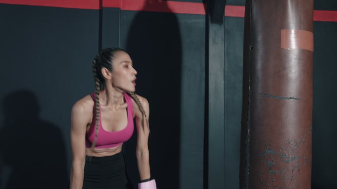 在拳击比赛中，亚洲年轻女子在拳击袋上锻炼。