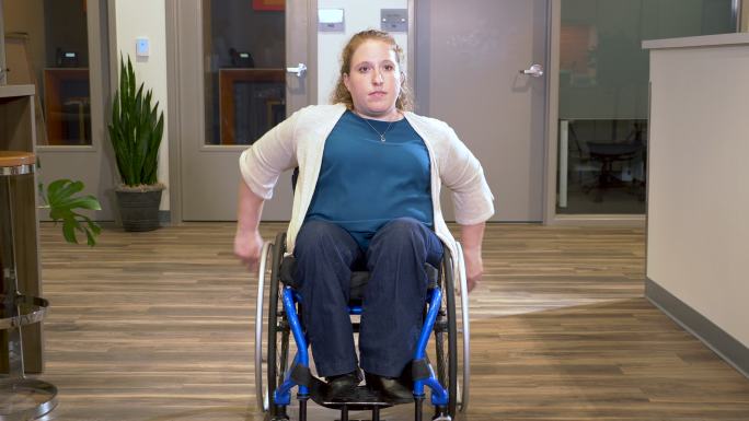 坐着自行轮椅在办公室里穿行的女性