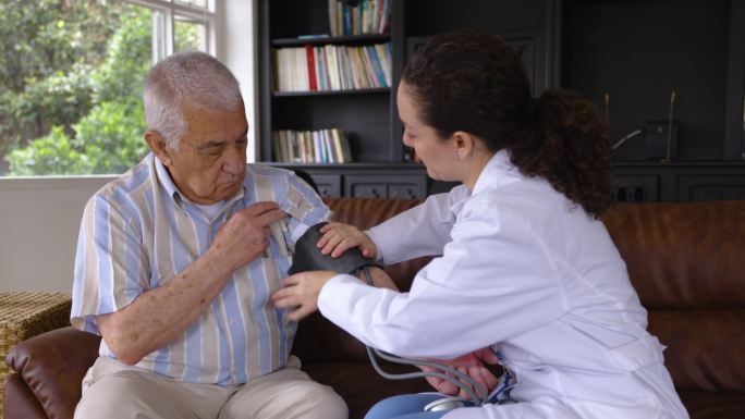 女医生在家里用血压监测仪检查老年患者