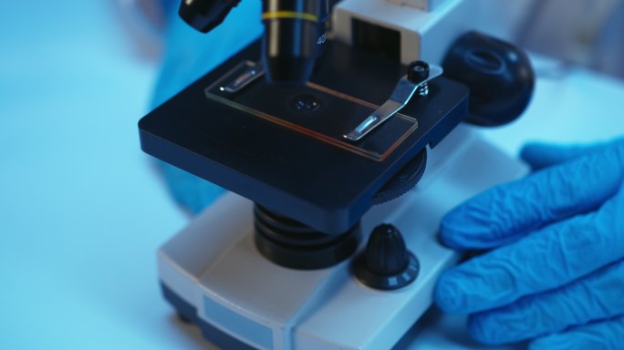 近距离观察显微镜中带有血滴的显微镜载玻片