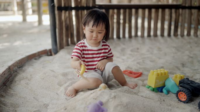 小女孩在沙坑里堆了一堆沙子