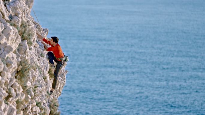 阳光下，人们攀登在海面上的锯齿状悬崖上