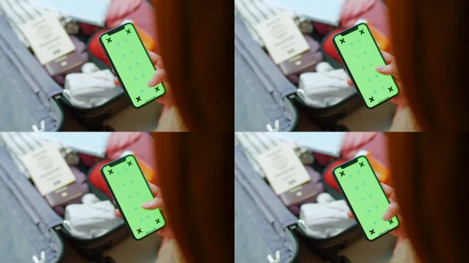 女性在打包行李箱时使用手机绿屏