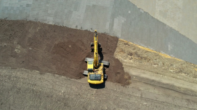 带有连续履带的黄色挖掘机。鸟瞰图。右旋转摄像机移动和缩小。整地挖掘机。施工现场准备。不同土层。加注挖