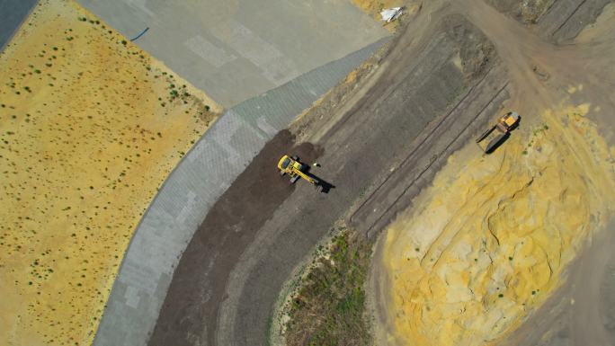 带有连续履带的黄色挖掘机。鸟瞰图。向上移动相机。整地挖掘机。施工现场准备。卡车不同土层。