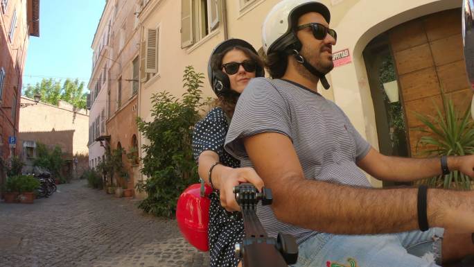 意大利罗马，一对年轻夫妇在骑红色摩托车时录制视频