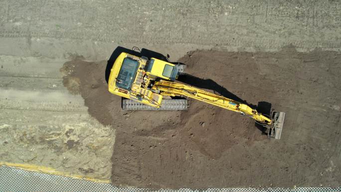 带有连续履带的黄色挖掘机。鸟瞰图。整地挖掘机。施工现场准备。清空挖掘机铲斗。