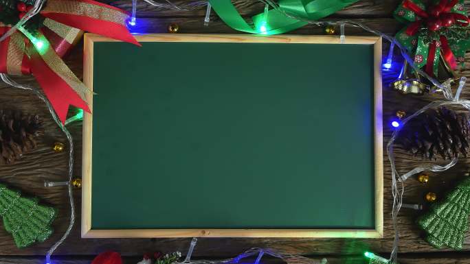 空的绿色板放在用圣诞装饰品装饰的木桌上。俯视图