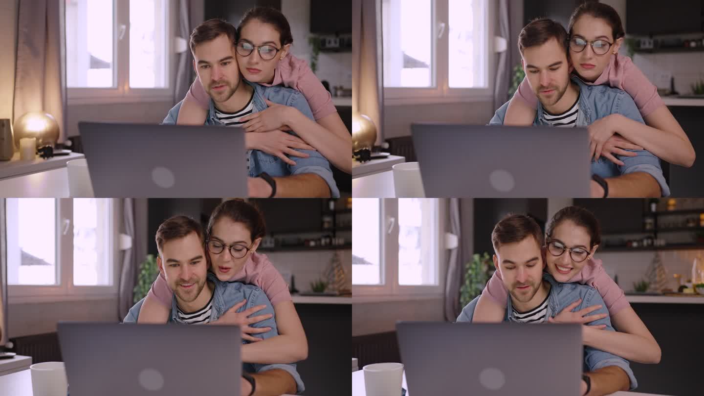 当男人在家工作时，爱她的年轻女人拥抱着他