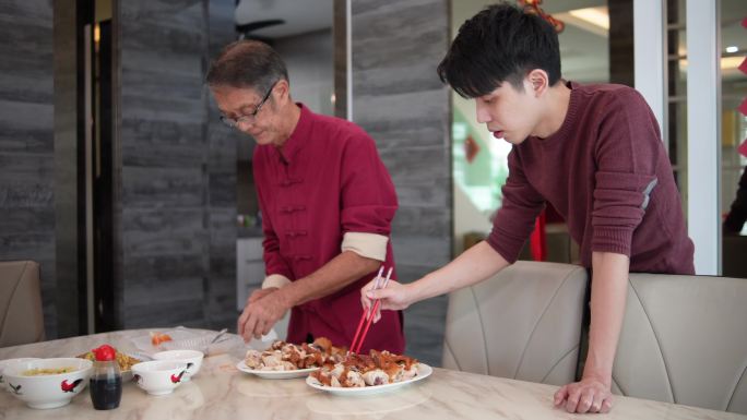 春节期间，亚洲中国年轻人和父亲一起在餐桌上准备食物