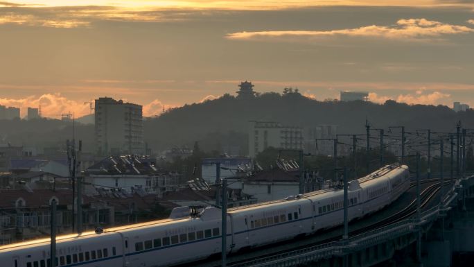 日出阳光下在城市中穿行的高铁火车