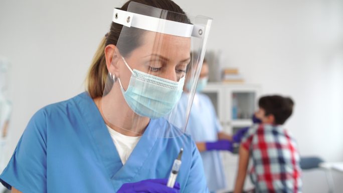 4K视频：医生戴着医用手套和口罩，手持COVID 19疫苗，用于预防和治疗新的冠状病毒感染