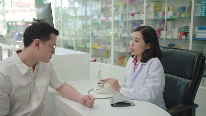 亚洲女药剂师正在对一名男性患者进行血压测量测试