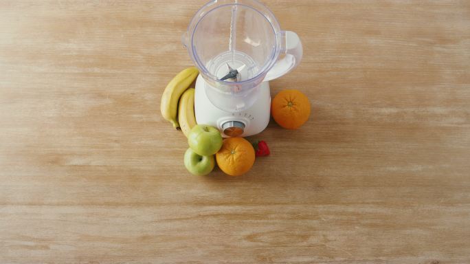 木制桌子上出现的新鲜农产品和其他健康奶昔配料的俯视图。水果、杏仁和配料与搅拌机一起制作冰沙。健康饮食