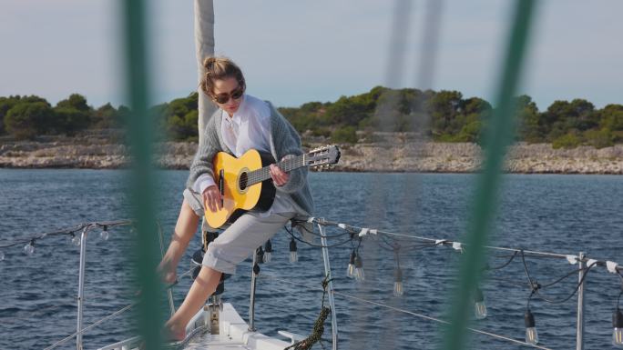 WS年轻女子在帆船的船头上弹奏原声吉他