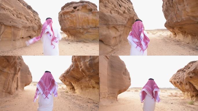 一名沙特男子在侵蚀岩层之间的沙漠中行走