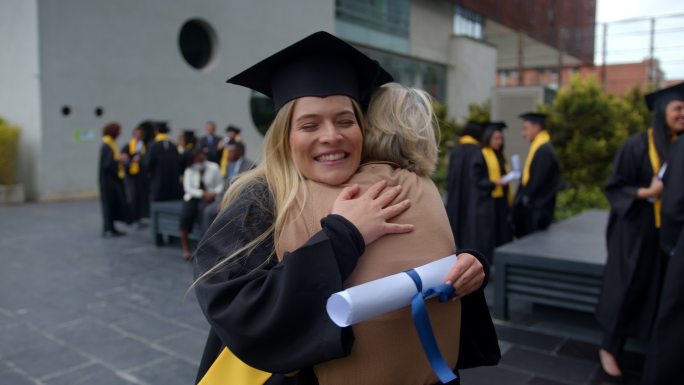 骄傲的妈妈兴奋地拥抱着刚刚大学毕业的女儿